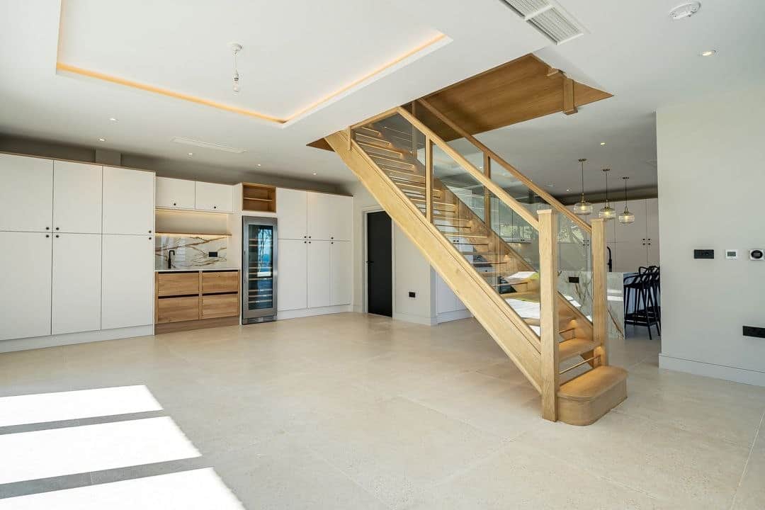 Bespoke oak staircase beside fitted kitchen joinery